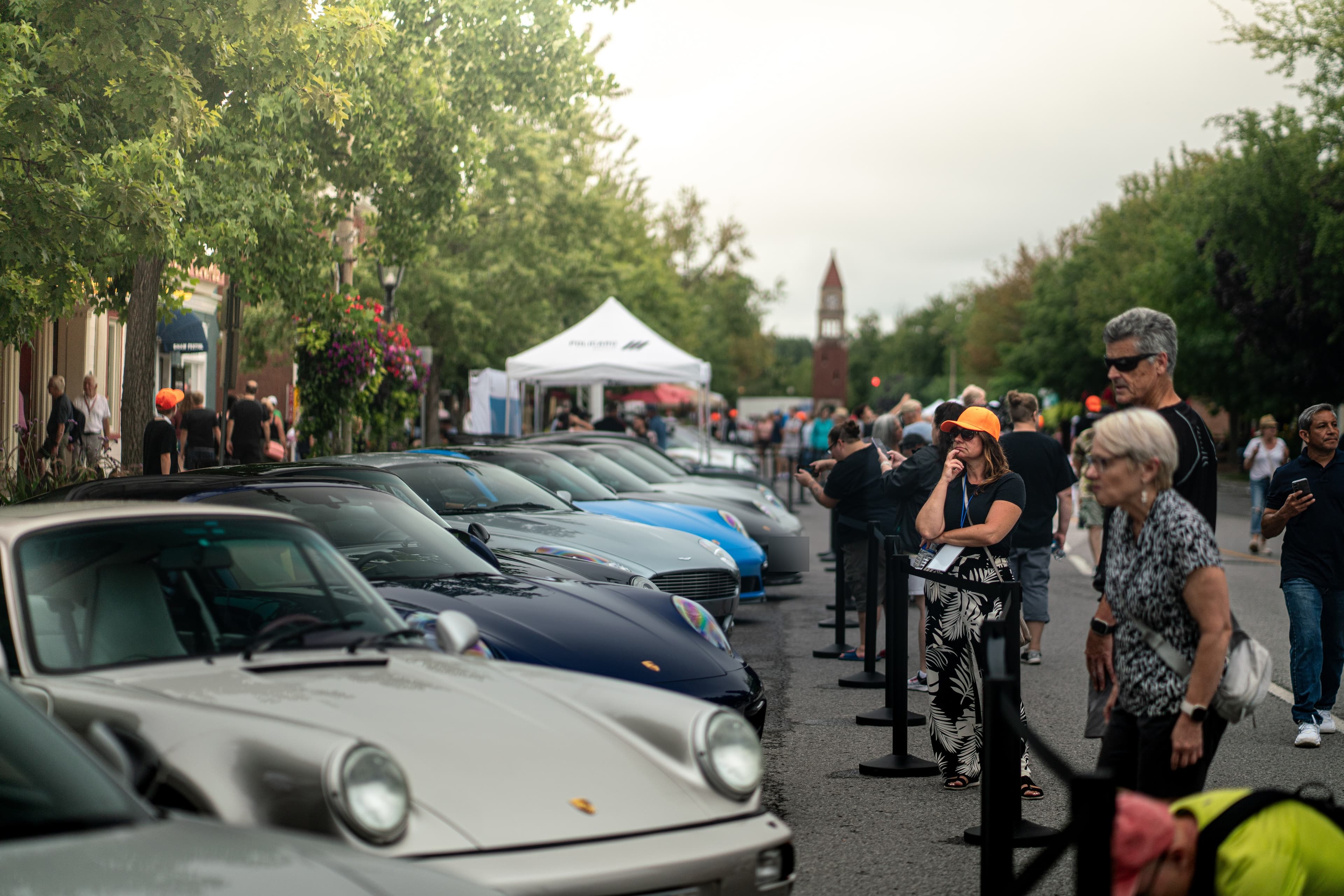 Spectators watch a row of Porsches parked along a Niagara-on-the-Lake street
